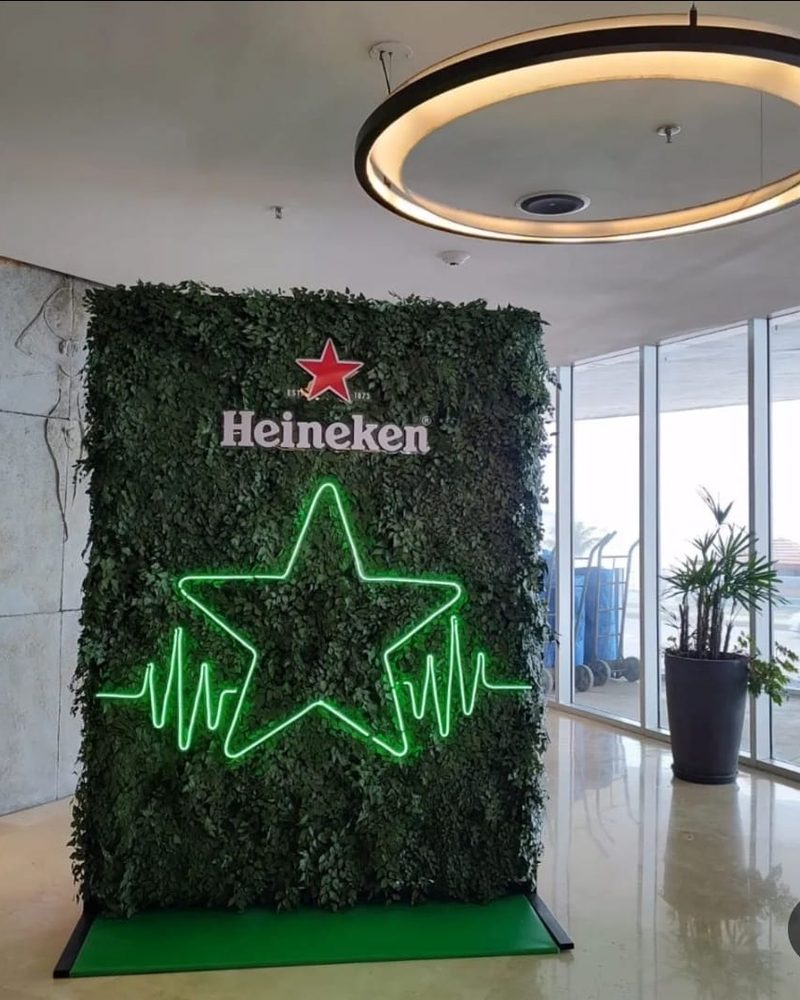 Painel de plantas artificiais Heineken com estrela neon em lobby amplo