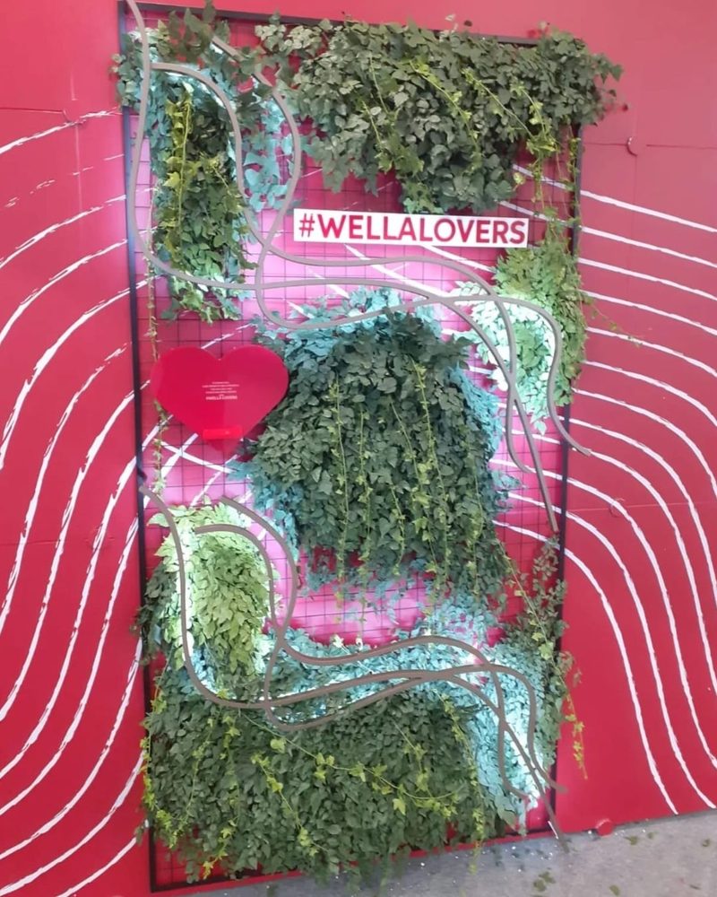 Backdrop temático #WellaLovers com heras artificiais